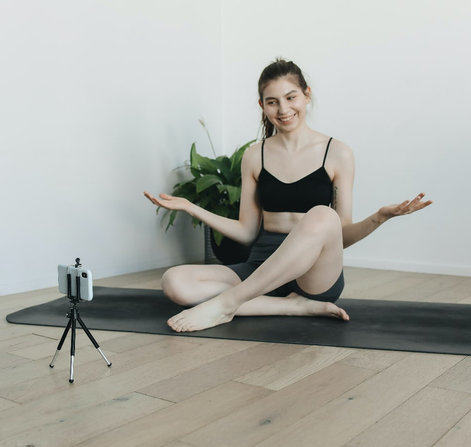 Ragazza sorridente segue lezioni di home fitness da smartphone